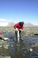 Researcher adds 'tracer' to a stream running into Lake Fryxell in McMurdo Dry Valleys. Photo by Emily Stone. Image courtesy of NSF/USAP Photo Library.
