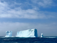 An iceberg drifts in the ocean near a Research Vessel. Photo by Cindy Dean, courtesy of the NSF/USAP Photo Library.