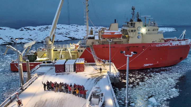 People gather on a dock in front of a ship in Antarctica
