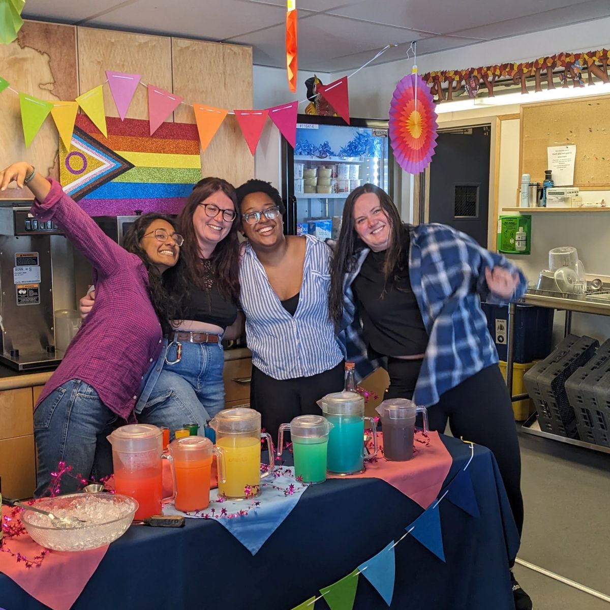 USAP Participants pose by a table with refreshments to celebrate 2023 Pride Day