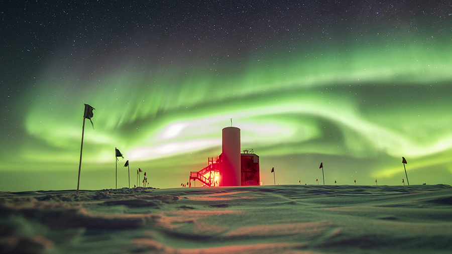A red building against a night sky filled with green auroras.